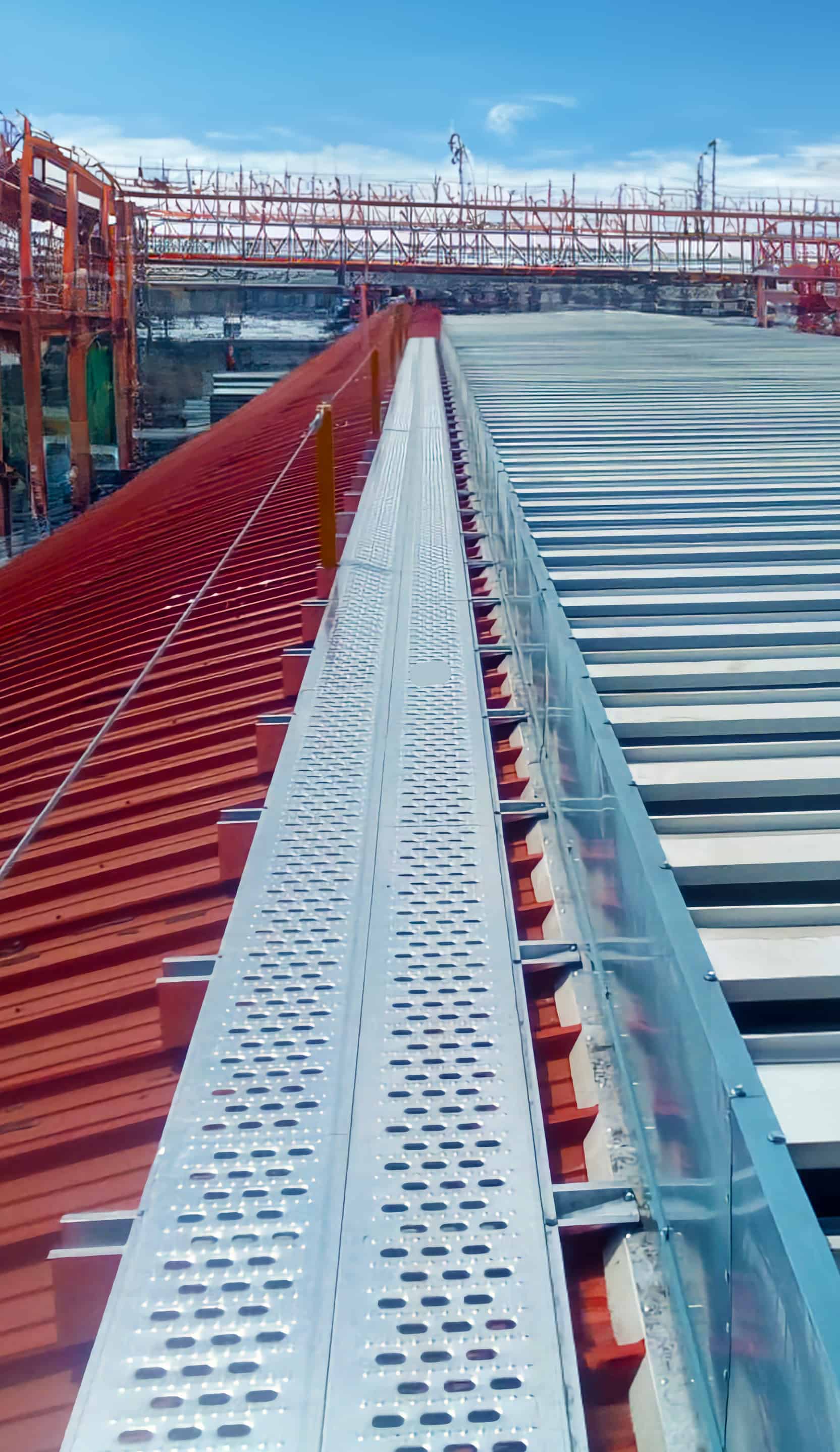 Hombre en un paso de gato arriba de una nave industrial caminando de manera segura en la industria