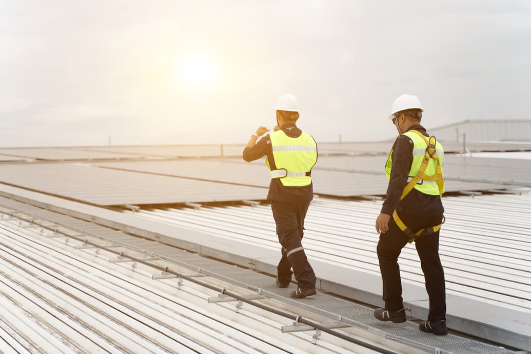 dos trabajadores que caminan a través de las industrias por medio de un paso de gato
