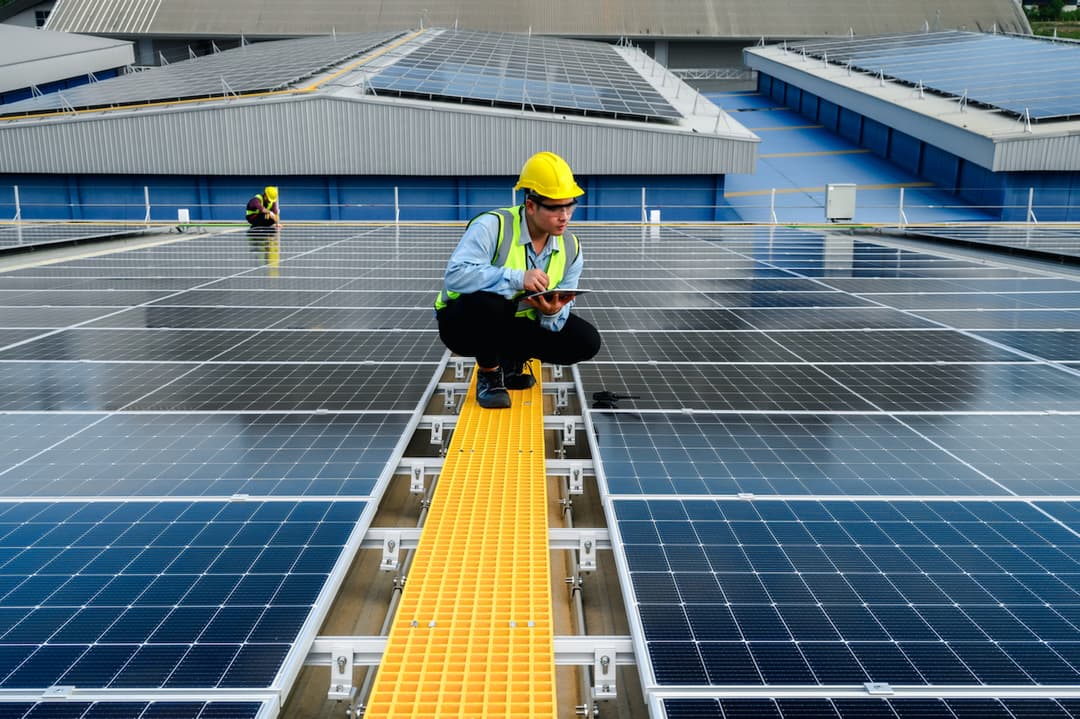 Ingeniero agachado mientras esta analizando los paneles solares