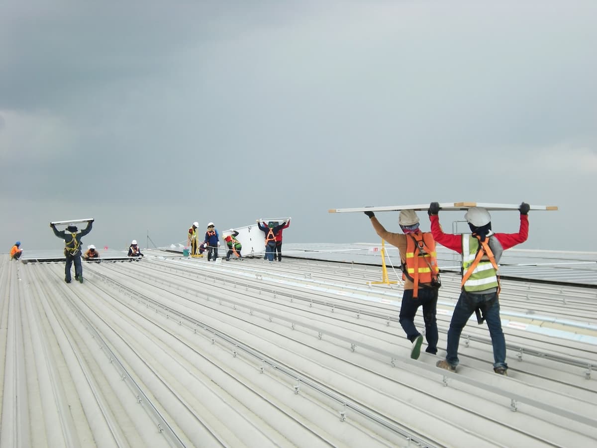 Trabajadores de una industria transportando paneles solares a través de un paso de gato